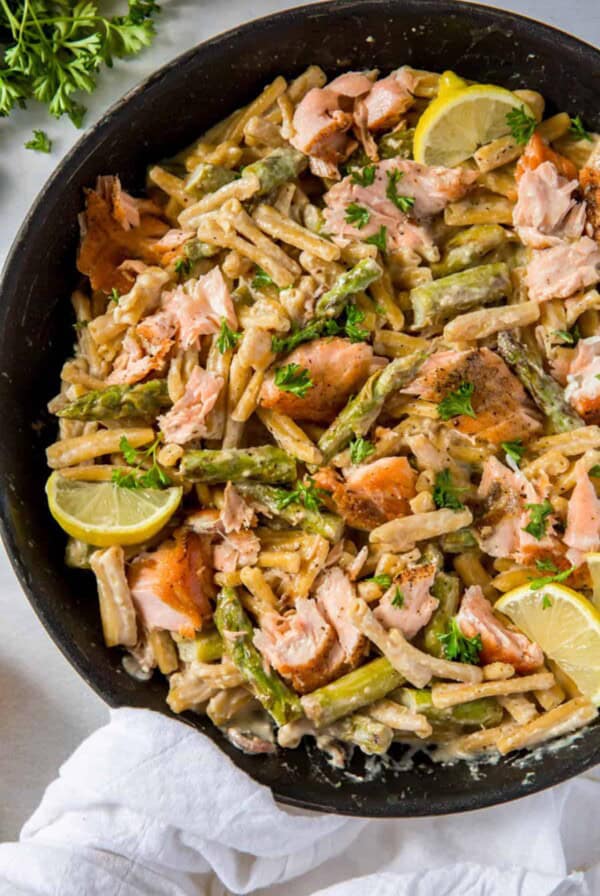 Creamy salmon pasta in a skillet cooked with asparagus, lemons and pasta.