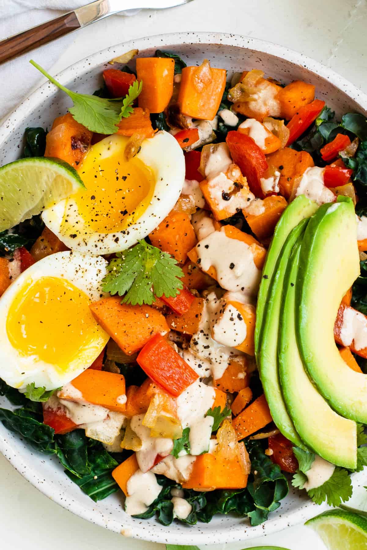 A close up photo of the sweet potato breakfast bowl with everything piled into a bowl and tahini drizzled on top.