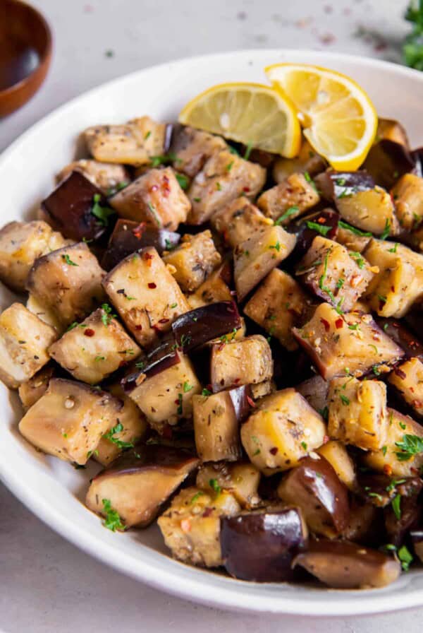 A white serving bowl with sautéed eggplant.