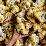 A spoon picking up sautéed cauliflower to serve.