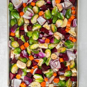 Raw cut up veggies on a pan for roasting.