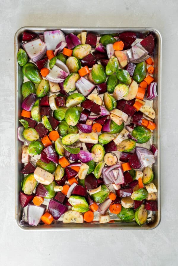 Raw cut up veggies on a pan for roasting.