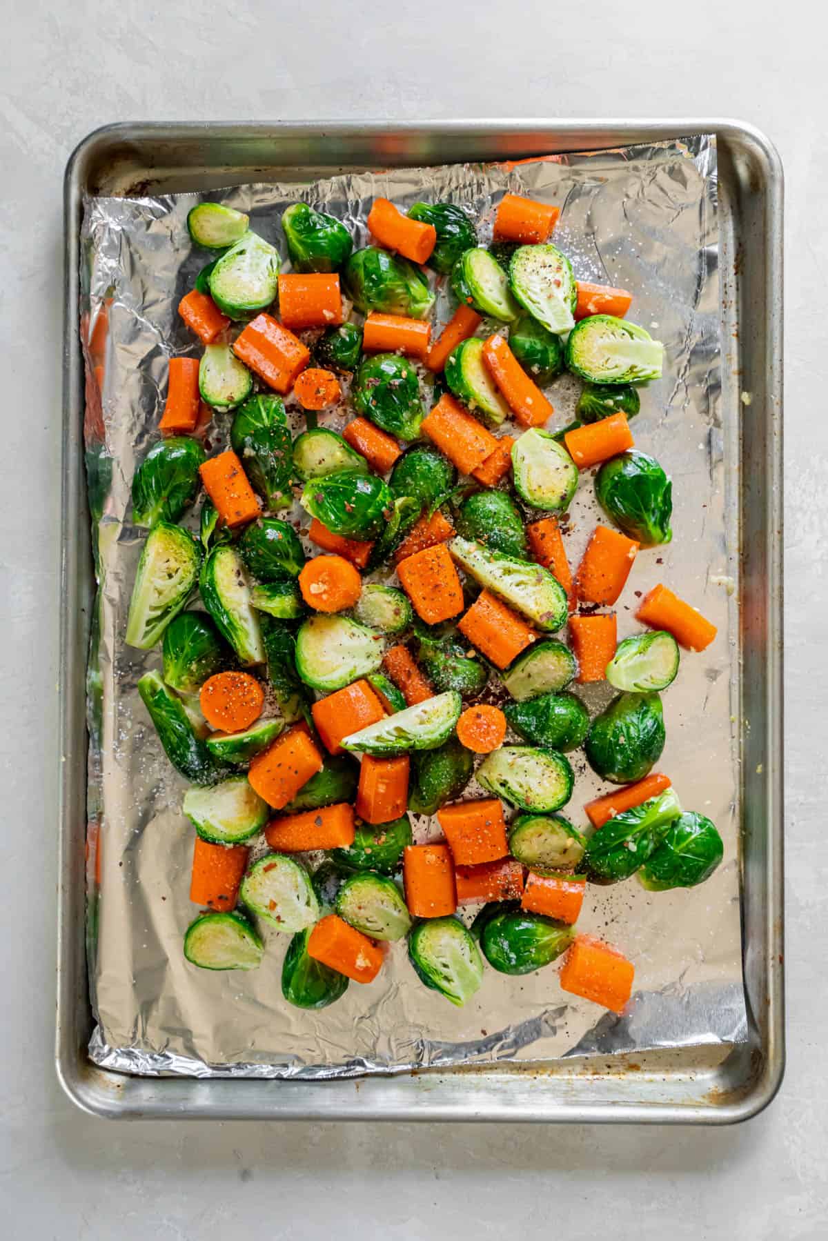 Cut brussels sprouts and carrots on a baking sheet ready for roasting. 