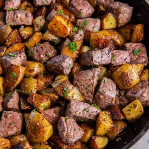 Garlic steak bites and potatoes in a cast iron pan ready for serving.