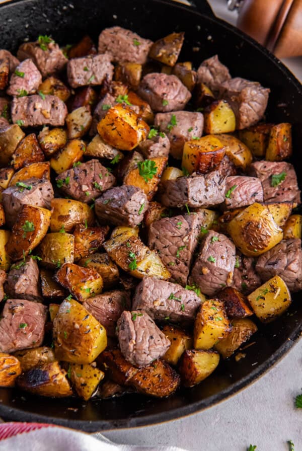 Garlic steak bites and potatoes in a cast iron pan ready for serving.