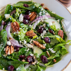 Spinach and arugula salad is in a white bowl ready for serving.