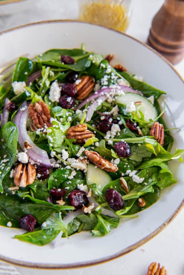 Spinach and arugula salad is in a white bowl ready for serving.