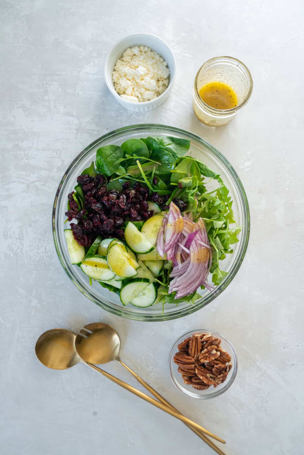 All of the ingredients for spinach and arugula salad in a bowl before mixing in the salad dressing. 