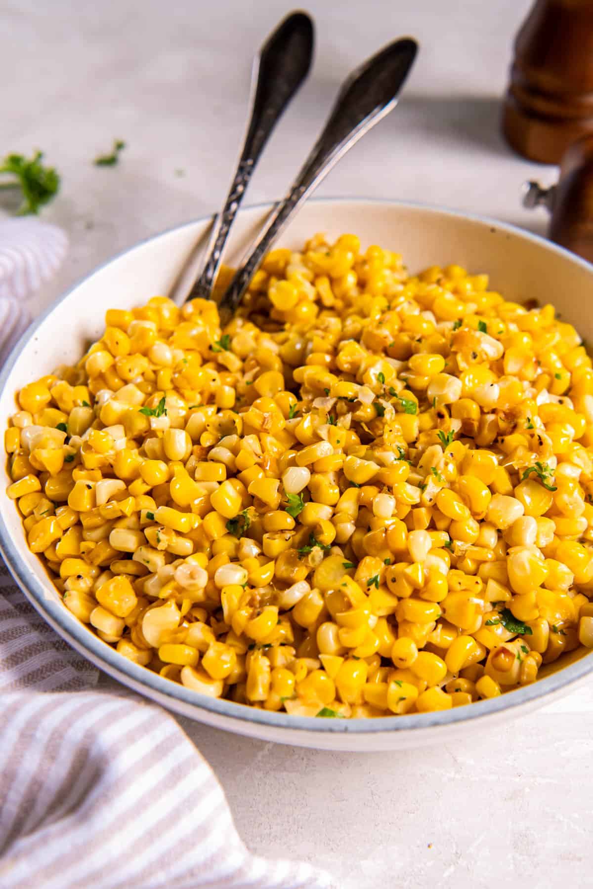 Skillet corn in a bowl with two serving spoons for serving. 