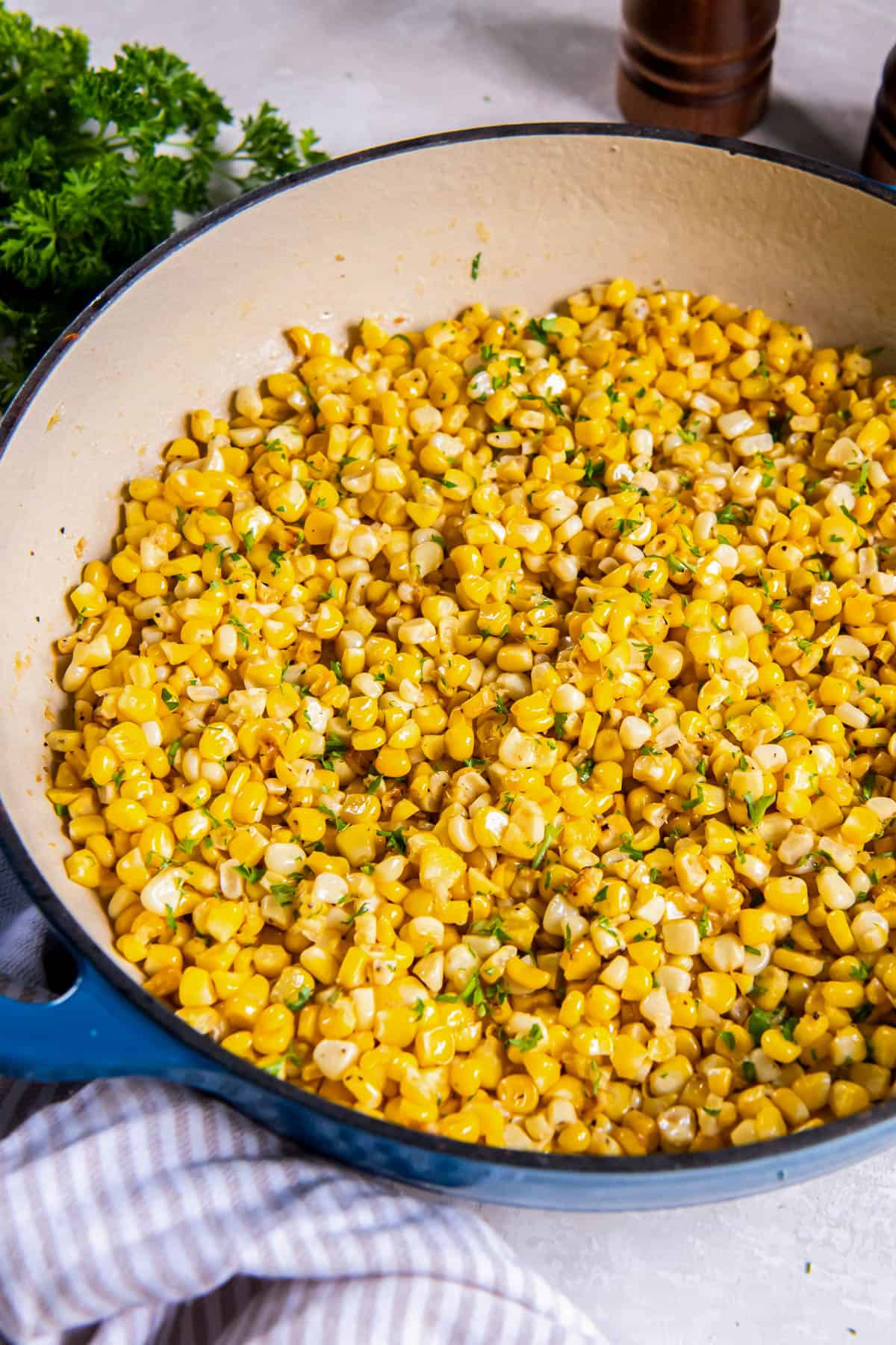 Sauteed corn in a skillet after cooking. Freshly chopped parsley is sprinkled on top as a garnish. 