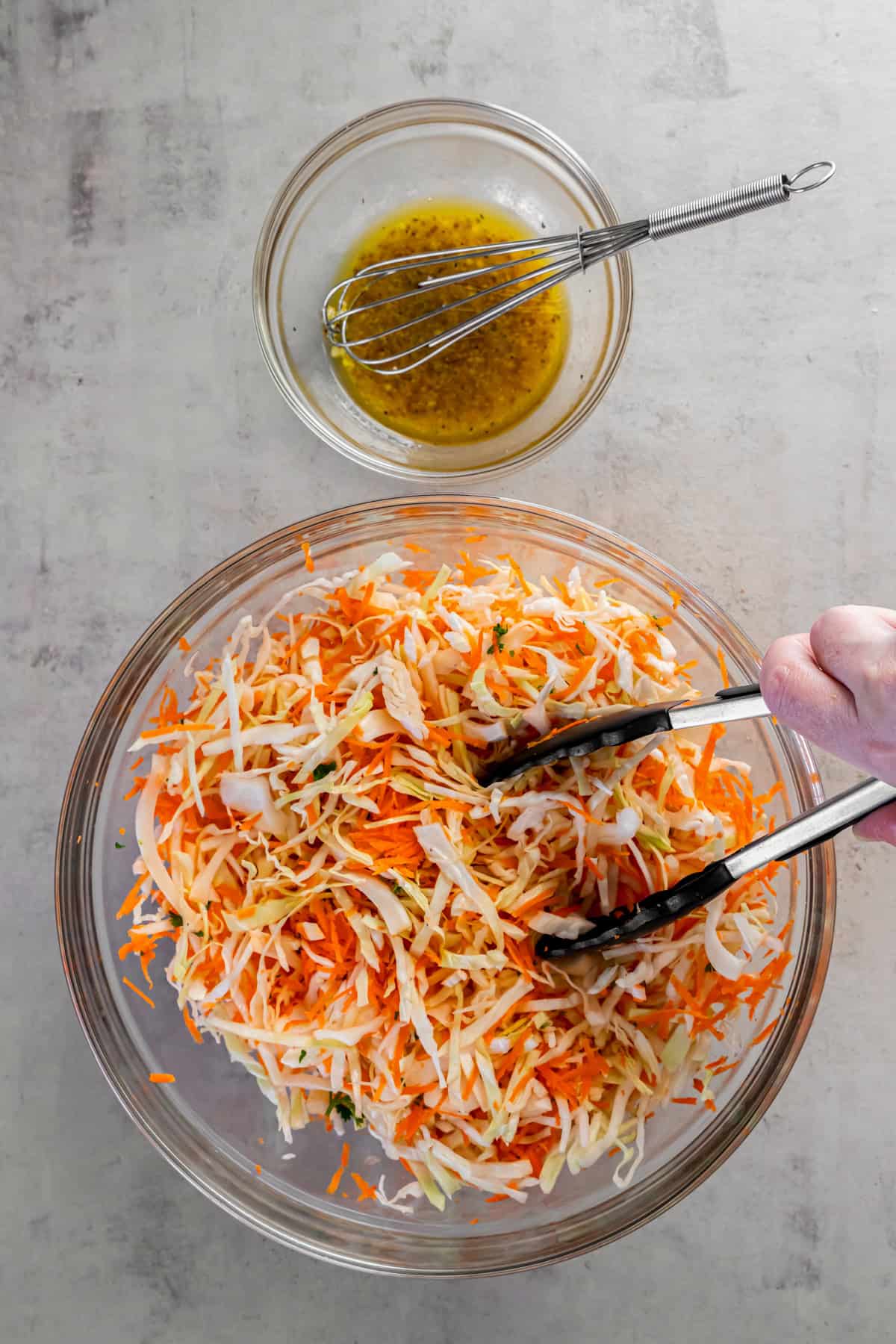 Tongs are used to mix together the dressing with the cabbage, carrots and parsley before serving.