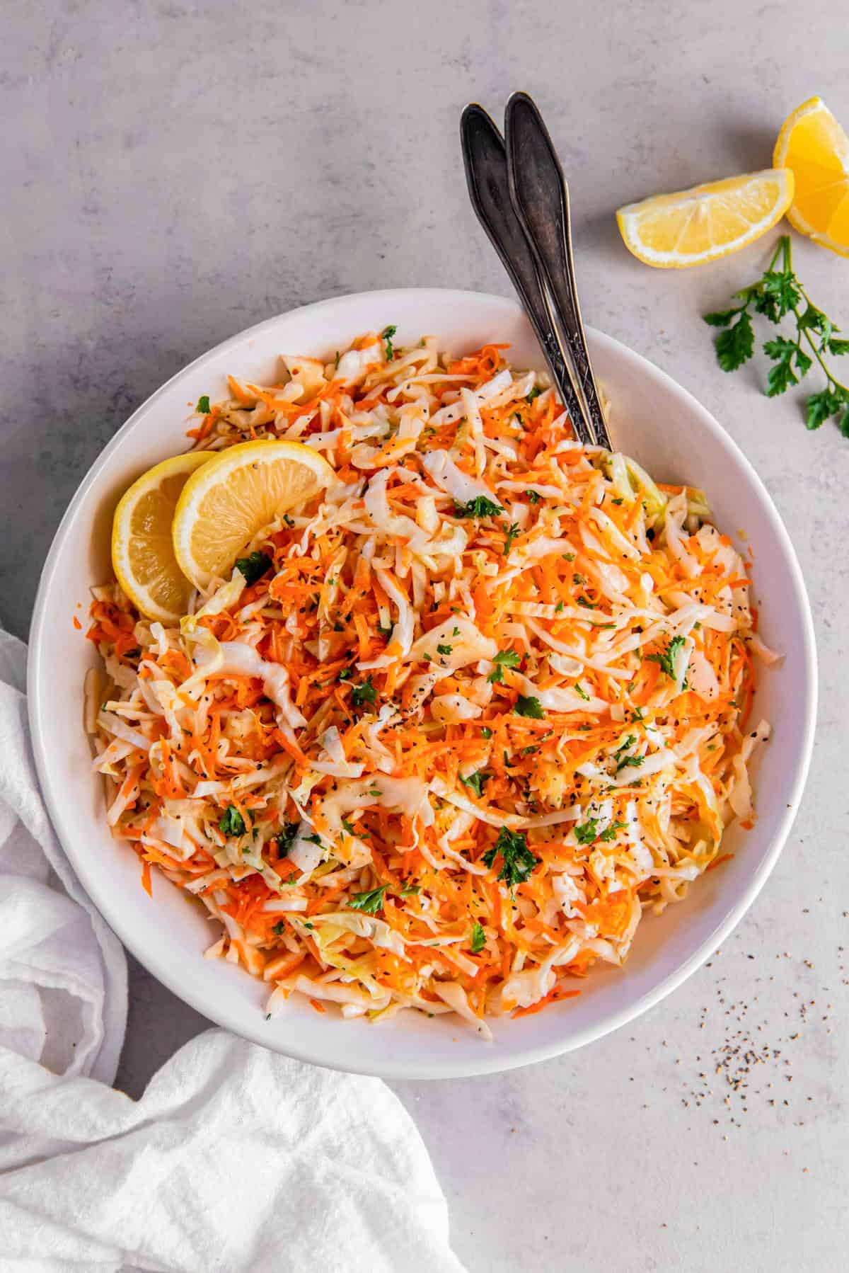 A white bowl with cabbage and carrot salad for serving.