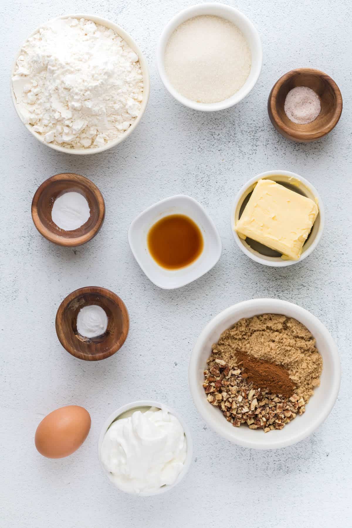 All of the ingredients for coffee cake muffins in bowls on a countertop for serving.