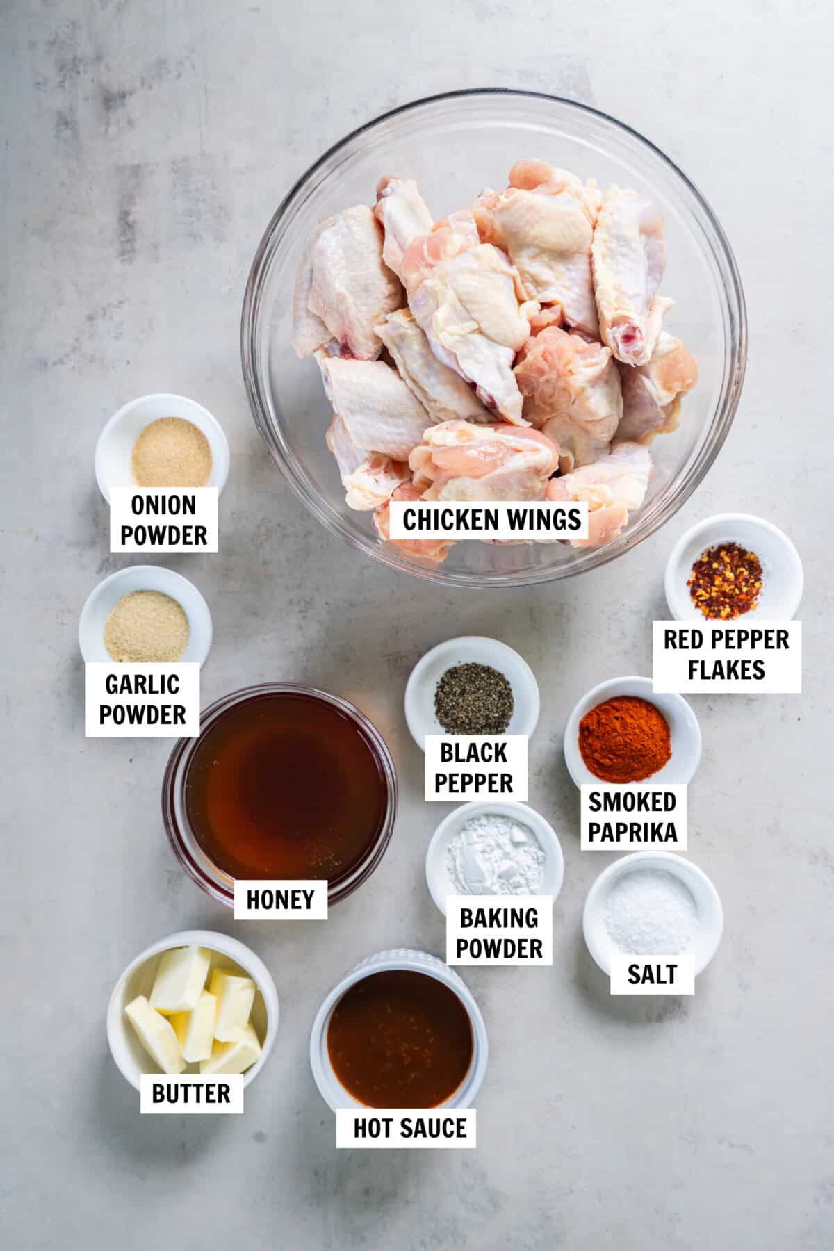 All of the ingredients for hot honey chicken wings in bowls on a white countertop. 