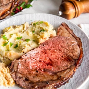 Delicious prime rib served with creamy mashed potatoes on a dinner plate, set on a festive table