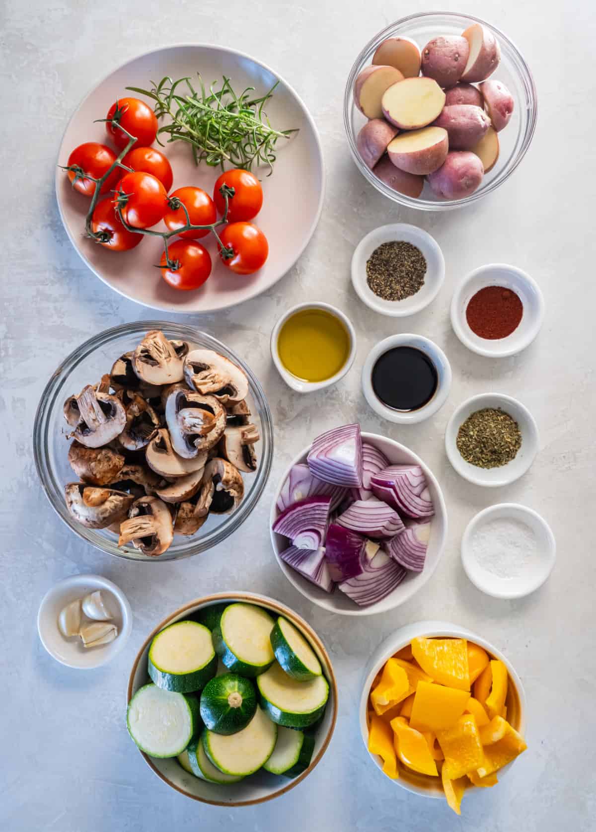 Ingredients in a bowl including zucchini, tomatoes, bell peppers, mushrooms, onions, garlic, and seasonings.